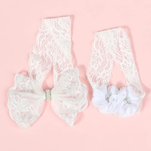 Détail de bandeaux bébé en dentelle blanche avec perles, strass et fleurs en tissu