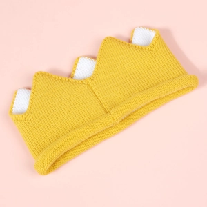 Detail of yellow knitted baby crown hat showing soft texture and crochet weave detail