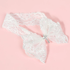 Gros plan d'un bandeau en dentelle blanche avec croix en strass argentés et nœud