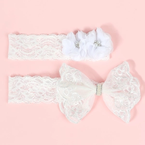 Détail de bandeaux bébé en dentelle blanche avec fleurs en tissu et strass étincelants