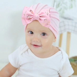 Detailed close-up of pink baby turban hat with a large golden star printed bow detail