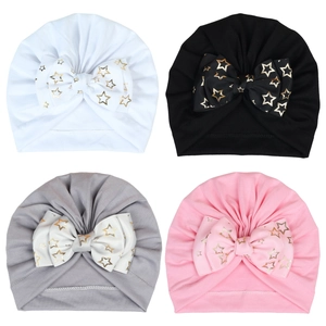 Detail of baby turban hats with large bows featuring gold star prints in four colors