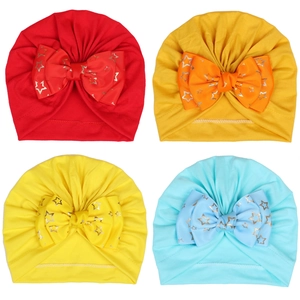 Detail of four colorful baby turban hats with large glittering gold star bow accents