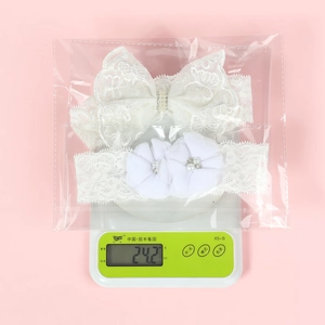 Mesure du poids de l'ensemble de 2 bandeaux bébé en dentelle blanche avec perles et strass