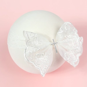 Détail du bandeau en dentelle pour bébé avec nœud et croix en strass étincelants