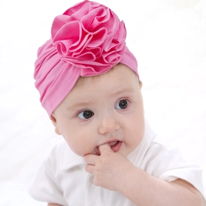 Detailed view of rose pink baby turban hat featuring a large 3D knit flower accessory