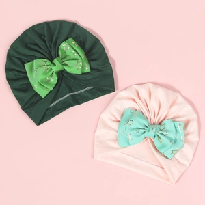 Detail of baby turban hats with large bows and golden star patterns in green and pink