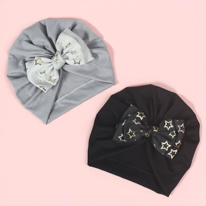 Infant Indian beanies in grey and black featuring gold star bows on pink background