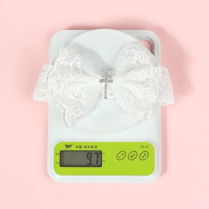 Détail d'un bandeau en dentelle blanche avec nœud et croix en strass sur une balance