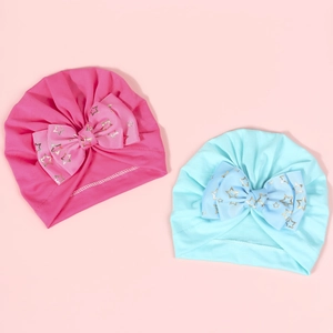 Detail of rose red and blue baby turban hats featuring golden star patterned bows