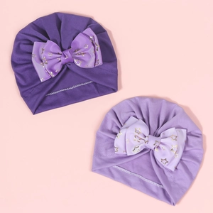 Detailed view of baby hats in dark and light purple with gold star bow patterns