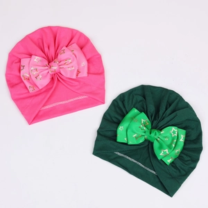 Detailed close-up of baby turban hats with large golden star bows in rose and dark green