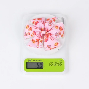 Close-up of pink Easter bow hair clip with colorful egg pattern and 9.0g weight display