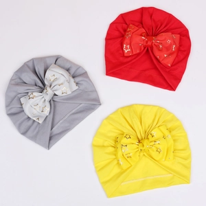 Detailed view of three baby turban hats with large gold star print bows in red, grey, and yellow