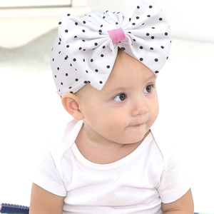 Détail du bandeau bébé avec nœud à pois noirs et blancs et centre en ruban rose