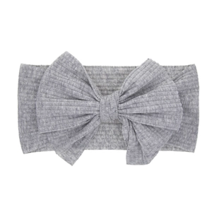 Bandeau bébé gris clair en maille côtelée avec un grand nœud sur un fond blanc épuré