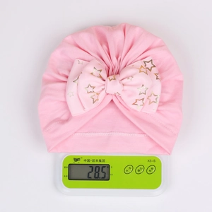 Pink infant turban hat with golden star bow detail showing a lightweight 28.5g mass