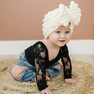 Close-up of baby turban hat featuring textured bubble fabric and a large cream bow