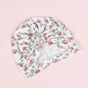 Détail du turban pour bébé blanc avec imprimé floral rouge et grand nœud décoratif élégant