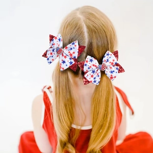 Detail of glitter patriotic bow clips with sequin trim on girls pigtail hairstyle