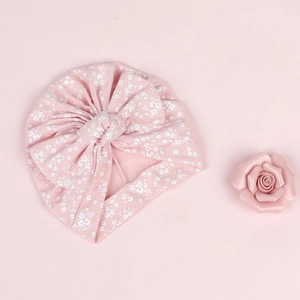 Vue détaillée du bonnet turban pour bébé avec imprimé floral rose et grand nœud décoratif