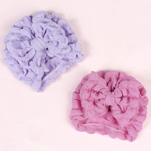 Detail of baby turban hats with large bows in purple and pink textured fabric
