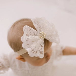 Détail d'un bandeau en dentelle blanche avec perles et strass pour bébé sur modèle