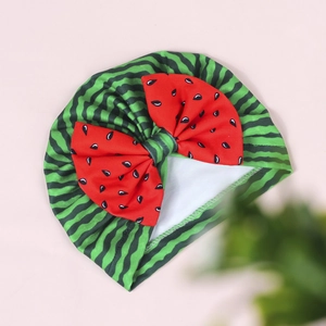 Detailed close-up of baby watermelon turban hat with green stripes and red bow
