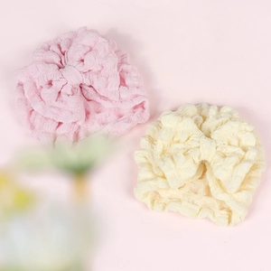 Close-up of pink and beige baby hats featuring large bows and soft bubble texture fabric