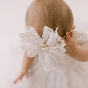 Vue détaillée du bandeau en dentelle pour bébé avec nœud blanc et décoration de perles