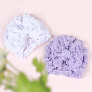 Detail of baby turban hats with large bows and textured bubble fabric in white and purple