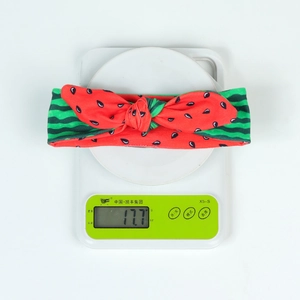 Watermelon bow baby headband weighing 17.7g on electronic scale for product weight demo