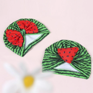 Detailed view of two baby watermelon turban hats with bow and printed seed patterns
