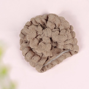 Close-up of textured bubble fabric and elastic seam on a camel brown baby turban hat