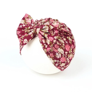 Detail of burgundy floral baby turban hat featuring a large soft decorative bow