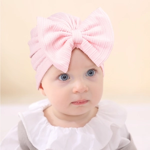 Detailed view of baby turban with large pink bow and soft ribbed knit texture
