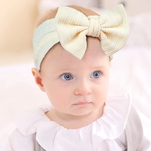 Close-up of baby headband featuring a large bow and soft ribbed knit texture in beige