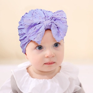 Close-up of a purple lace baby turban hat with a large bow and ruffled edge detail