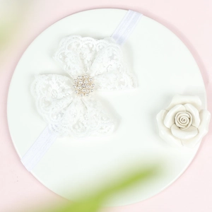 Gros plan du bandeau en dentelle blanche avec centre en perles et strass brillant
