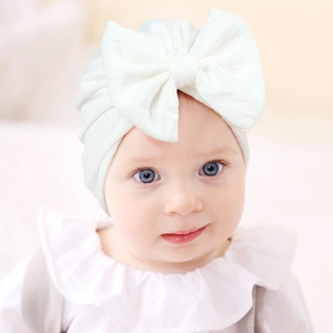 Detailed view of white newborn baby turban featuring elastic textured fabric and large bow