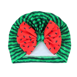 Infant turban hat with watermelon pattern and a large red decorative bow on front