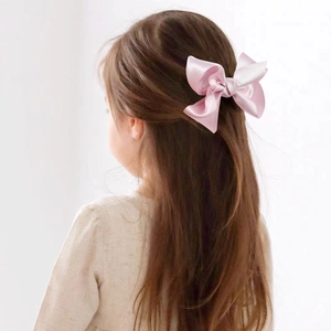 Detail der rosa Satin-Haarschleife am Haar eines Kindes mit geschichteter Textur