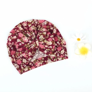 Close-up of baby turban hat with red floral pattern and large decorative bow detail