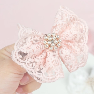 Vue détaillée d'un nœud en dentelle rose avec perles blanches et accents de cristal