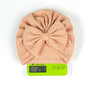 Detail view of pink newborn knot hat weighing 29.6g on a digital scale for lightweight proof