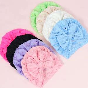 Lace baby turbans set with large bows showing multiple colors on a soft pink background
