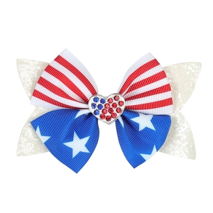 Close-up of patriotic American flag hair bow with glitter sequins and heart rhinestone