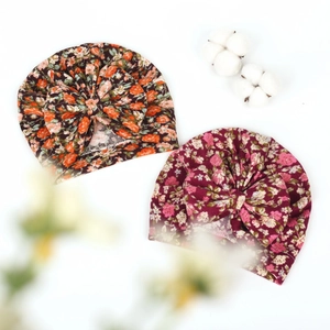 Close-up of baby floral turbans with large bows in orange and pink stretchy cotton fabric