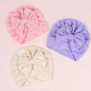 Detail of baby turban hats featuring large bows and soft pleated lace fabric texture