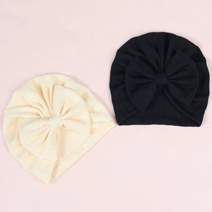 Elastic baby turban hats with large bows in cream and black colors, ribbed knit style